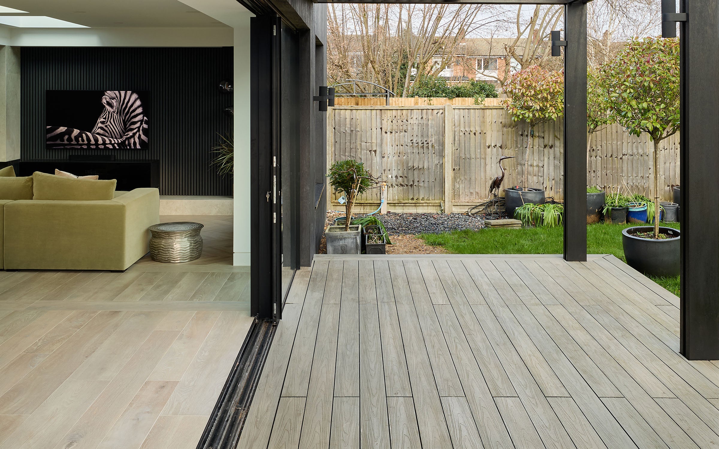 modern outdoor living space with a composite deck, garden, and house interior.